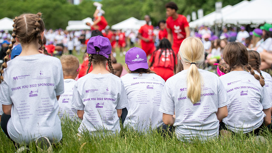 Chidren sit in the grass watching the Jesse White Tumblers