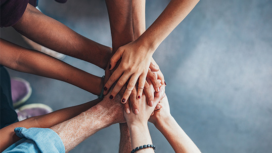 A group of hands meet together in the center of a circle.