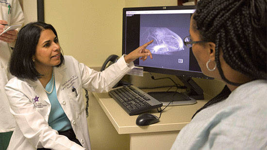 Doctor pointing to mamogram on computer screen