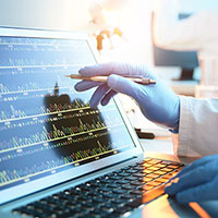 laptop screen with gloved hand pointing at data