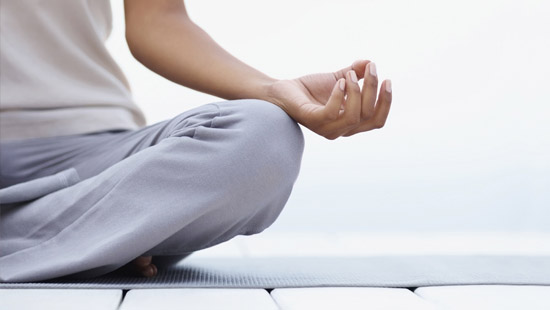 Someone sits in a cross-legged, meditative position.