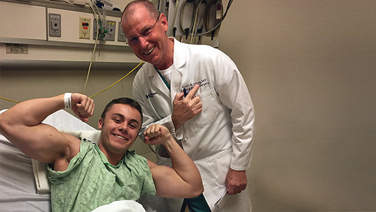 Male patient flexes bicepts and poses with his doctor