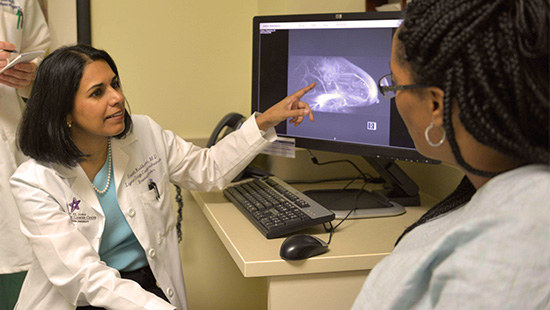 Doctor pointing to mamogram on computer screen